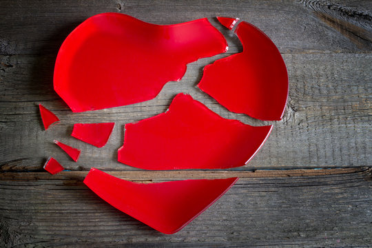 Broken heart red plate concept on wooden board