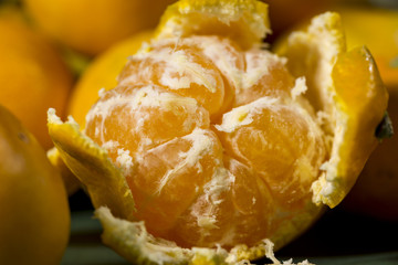 Close-up of half peeled orange tangerine between other citrus fruits