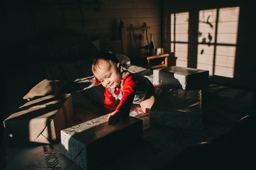 Fototapeta premium little boy sitting on the bed considering gifts
