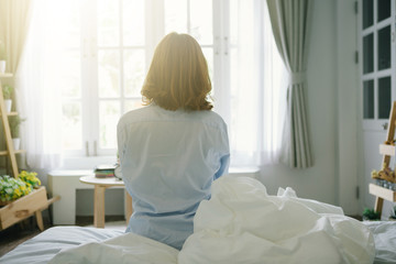 Woman sitting on bed after wake up,vintage tone,flare light