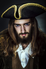 Portrait of a medieval bearded pirate on black background.