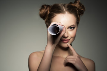 Beautiful girl looks in a telescope in the paper roll. Scouting