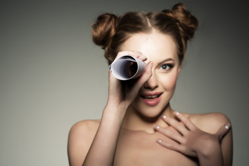 Beautiful girl looks in a telescope in the paper roll. Scouting