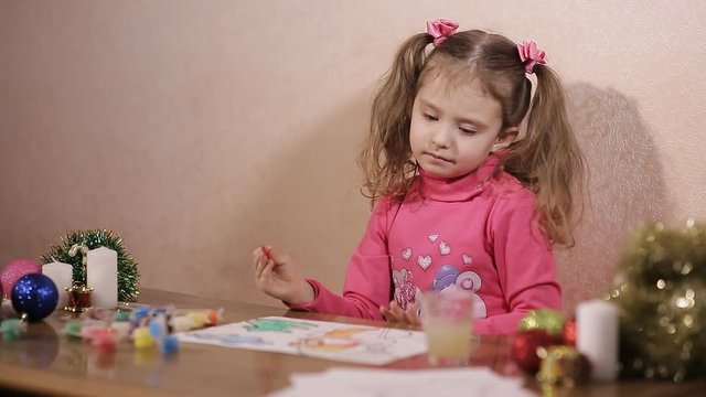 little girl draws paints a winter evening