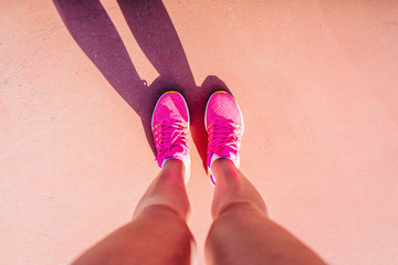 Summer day. View from above. Female feet. Girl dressed in bright pink sneakers.