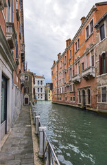 Fototapeta na wymiar Narrow canal among old colorful brick houses in Venice, Italy.
