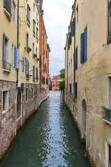 Fototapeta na wymiar Narrow canal among colorful brick houses in Venice, Italy.