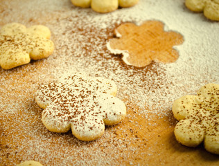 Homemade shortbread flower shape cookies with sugar powder on wooden table