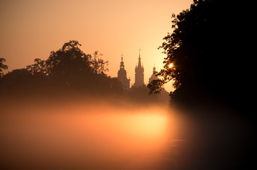 Misty Blonia meadow in Krakow, Poland, with St Mary's church and Town Hall towers in the background.