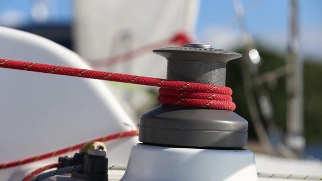 Sailing crew member on sailboat trimming front sail by winch