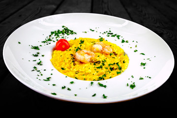 Dish with risotto, shrimp and tomato. Decorating parsley. Shot in studio with black background.