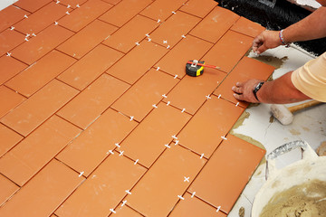 Bricklayer laying the new floor tiles in the courtyard of a house