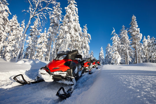 Group of red snowmobiles in Finnish Lapland sunny landscape