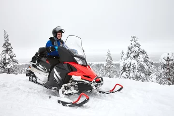 Fotobehang Happy smiling man driving snowmobile in Finnish Lapland © kobeza