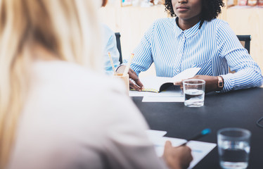 Closeup of beautiful womans making business meeting in modern office. Group girls coworkers discussing together new fashion project. Horizontal, blurred background.