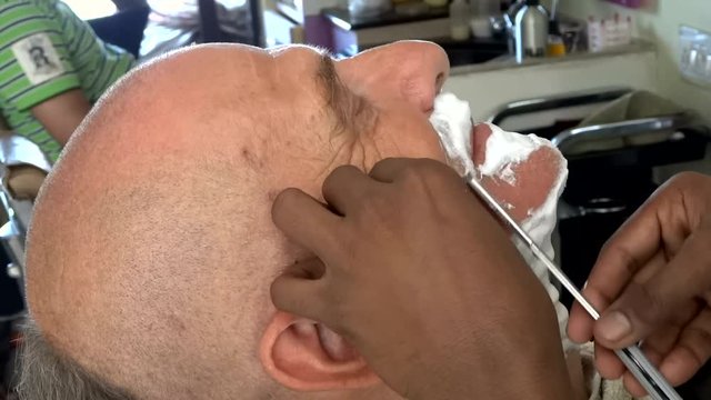 White italian man is doing the shave by indian barber