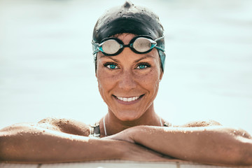 Portrait of Female Swimmer. Holding on pool edge and smiling