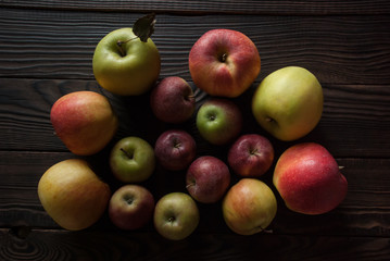 Colored apples of different sizes on a wooden surface