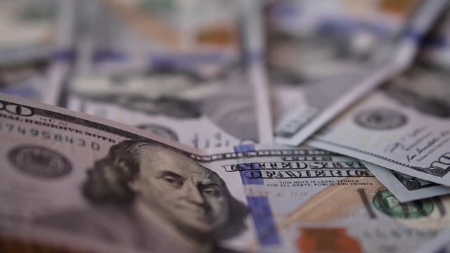 Backward direction close up dolly shot of scattered American paper money bills with a variety of denominations