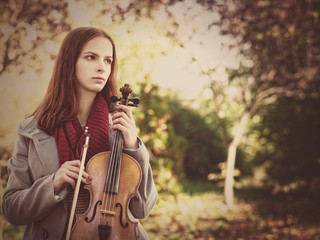Young beauty musician holding his violin, urban female portrait