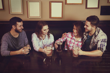 Happy friends drinking beer in pub