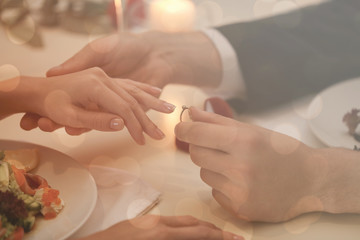 Obraz na płótnie Canvas Man making marriage proposal to girlfriend at restaurant, closeup