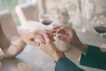 Man making marriage proposal to girlfriend at restaurant, closeup - obrazy, fototapety, plakaty