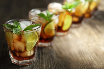 Glasses of cocktail with ice and mint on wooden background