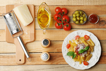 Delicious penne pasta with ingredients on wooden table