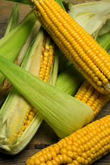 Ripe yellow sweet corn cob on a wooden table close-up