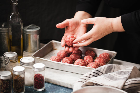 Beef swedish meatballs bowl. Female hand preparing beef meatballs in cooking sheet on marble board. rustic style.