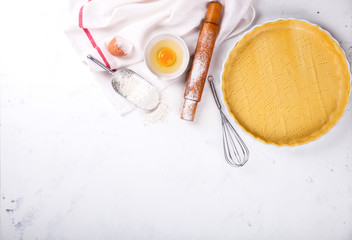 Baking Background. Ingredients  for baking - flour, wooden spoon, rolling pin, eggs, egg yolks, butter served, milk on white background.selective focus.Top view. Copy space.
