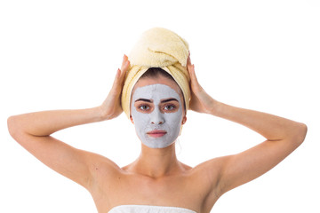 Woman with towel on her head and cosmetic mask on her face 
