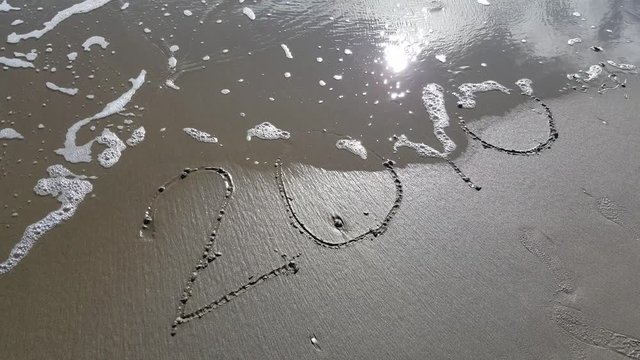 scritta 2016 sulla sabbia che viene cancellata dalle onde