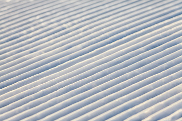 Diagonal snowcat track lines on a ski slope abstract texture background