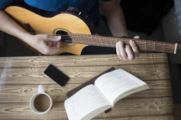 .Man teaching himself to play guitar at home