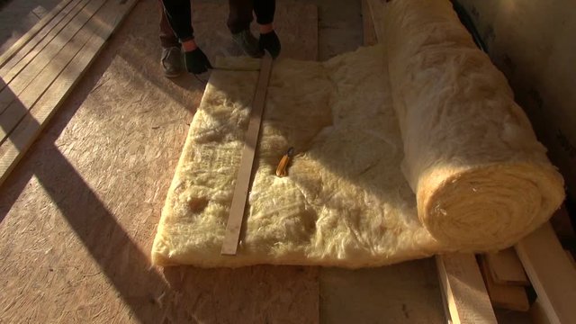 Builder measuring and cutting mineral rock wool for insulation