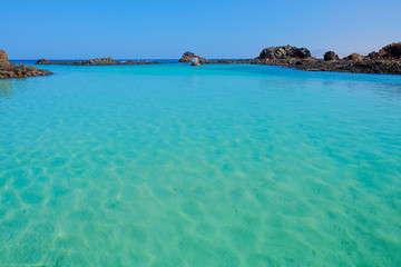 Lagoon with transparent blue water and a boat on Fuerteventura, Spain.