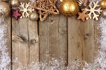 Gold Christmas ornament top border with snow frame on a rustic wood background