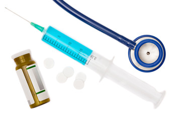 Stethoscope, syringe with blue liquid inside and pills studio shot on white