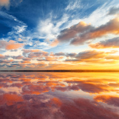 Naklejka na ściany i meble Beautiful sunset landscape. Cloudy sky above salt lake.