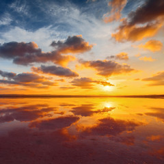 Beautiful cloudy sky above salt water lake. Scenic sunset landscape.