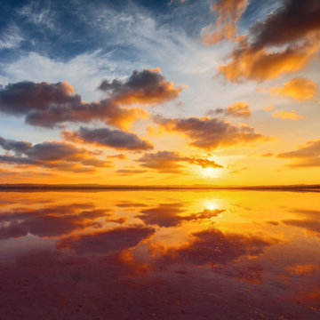 Beautiful cloudy sky above salt water lake. Scenic sunset landscape. © Maxim Khytra