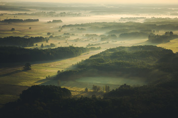 Fototapeta premium Sunrise fog over fields and forest landscape.
