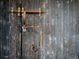 Rustic wooden gate with rusty padlock and lacth