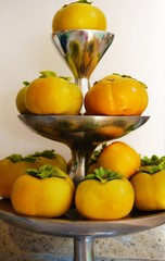 Orange persimmon kaki fruits freshly picked in the fall on a silver pedestal