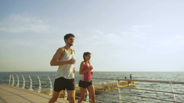 Young couple running on the wooden boardwalk.
