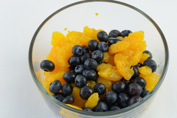 Fresh blueberries and canned mandarin oranges in glass bowl