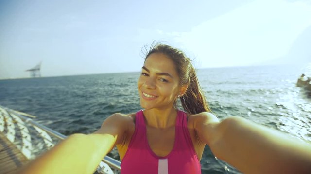 Funny young brunette taking selfies on the beach.
