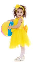 Little girl in yellow dress holding a ball